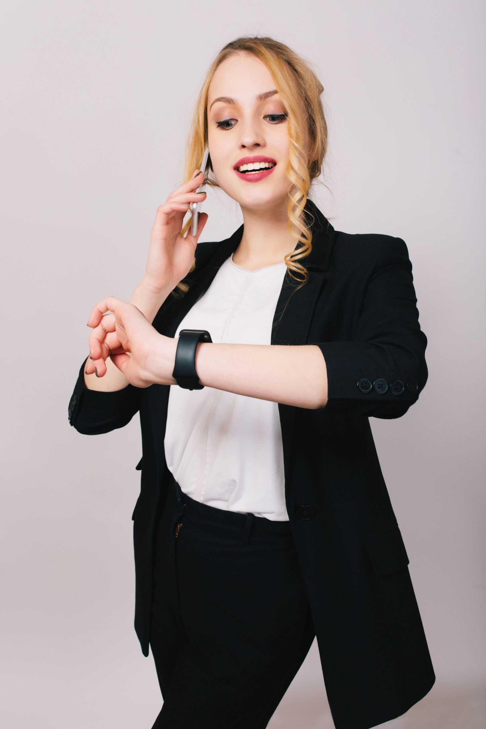 joyful pretty young businesswoman office suit talking phone smiling looking watch cheerful mood happy successful worker isolated corporate min